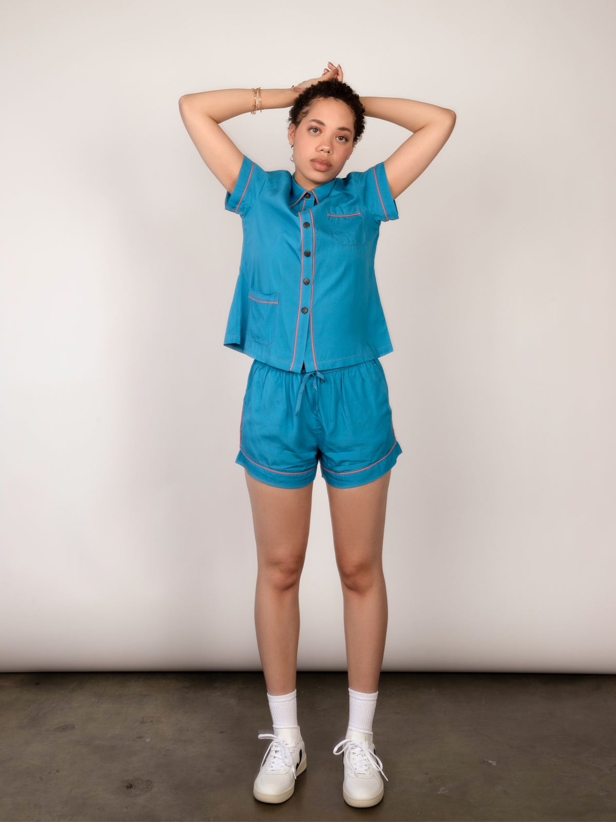 Woman stretches and poses wearing a blue short-sleeve pajama set.