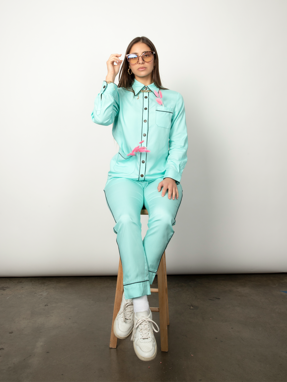 Woman poses wearing a teal long-sleeve pajama set and glasses.