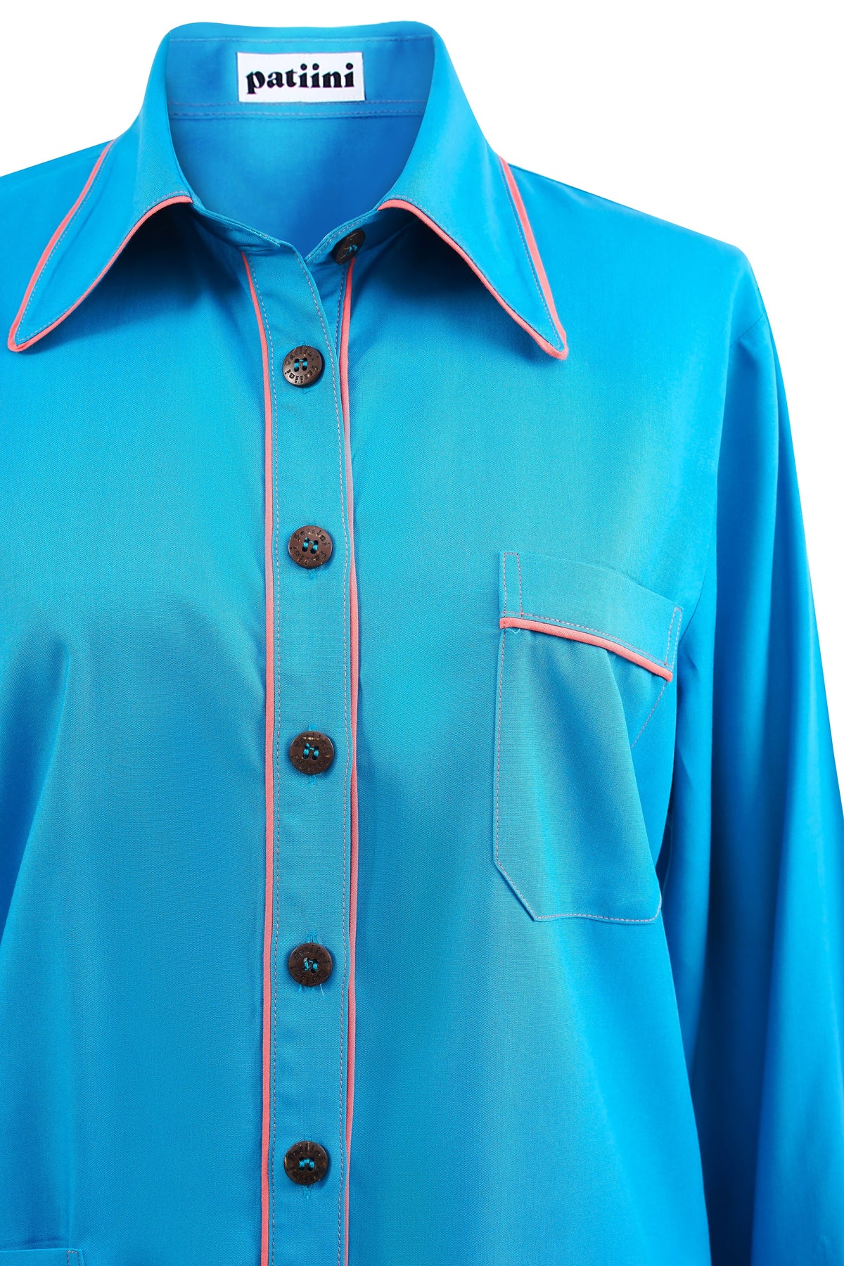 Close up of blue pajama shirt wiith coconut shell buttons and contrasting coral piping.
