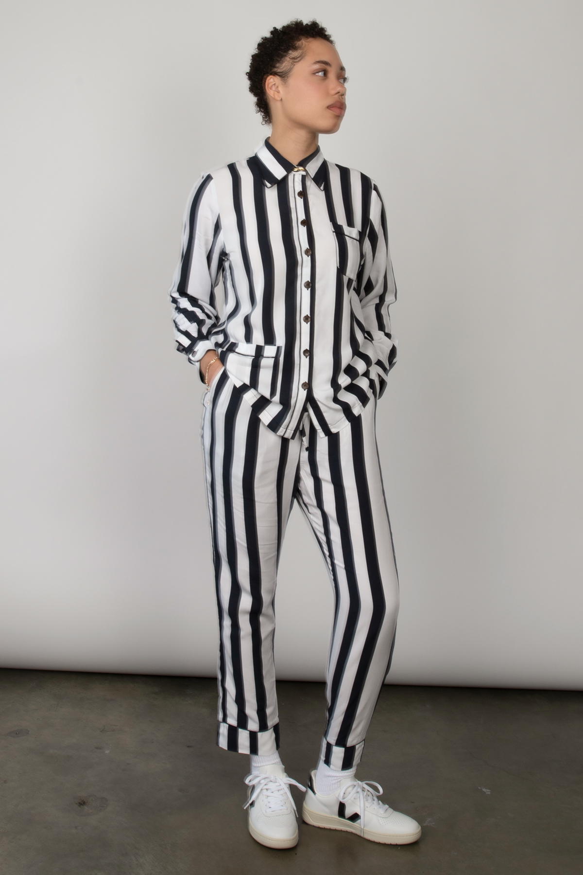 Woman wears a black and white striped long-sleeve shirt and poses in a studio.