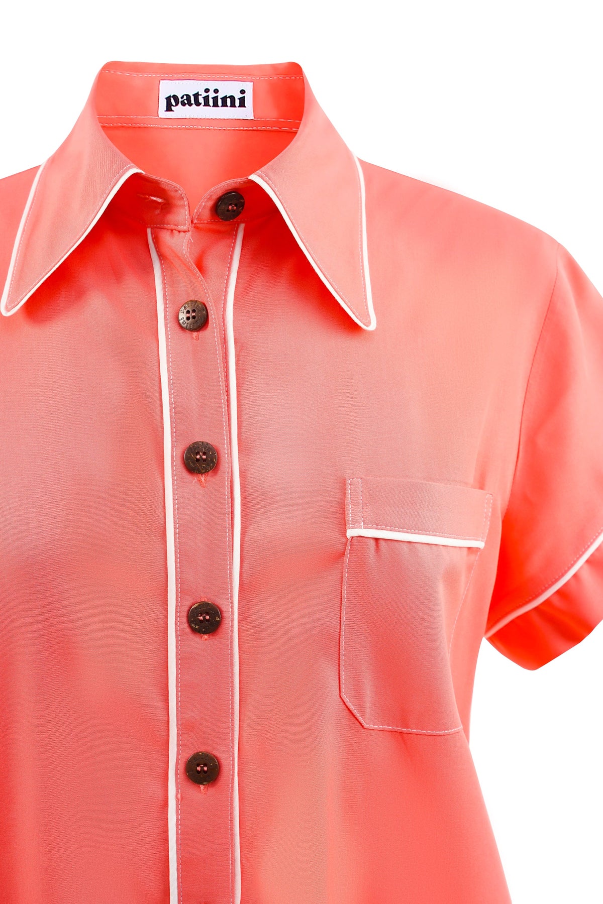 Close-up of a coral button-down shirt with coconut shell buttons.