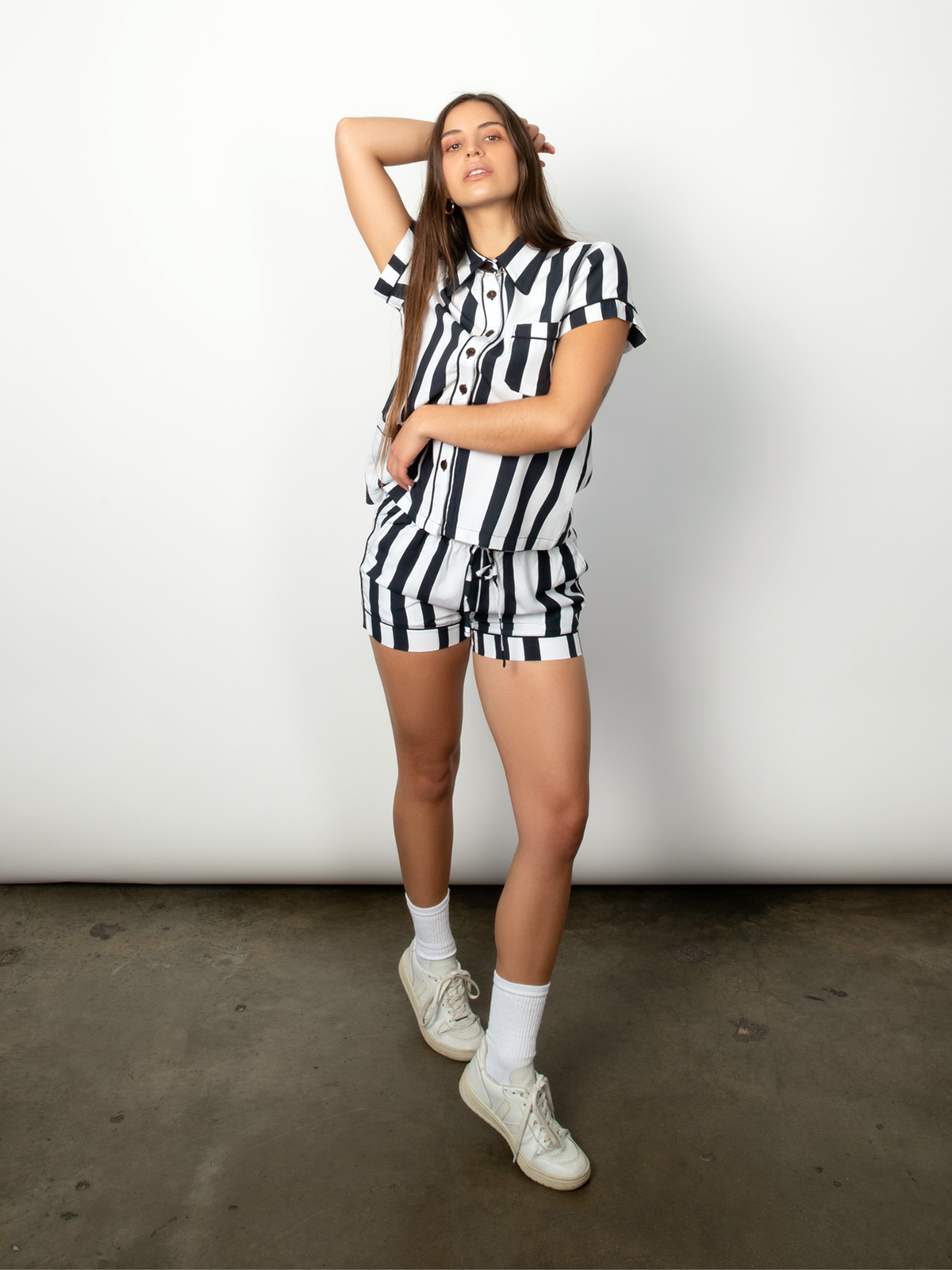 Woman wears a black and white striped short-sleeve shirt and poses in a studio.