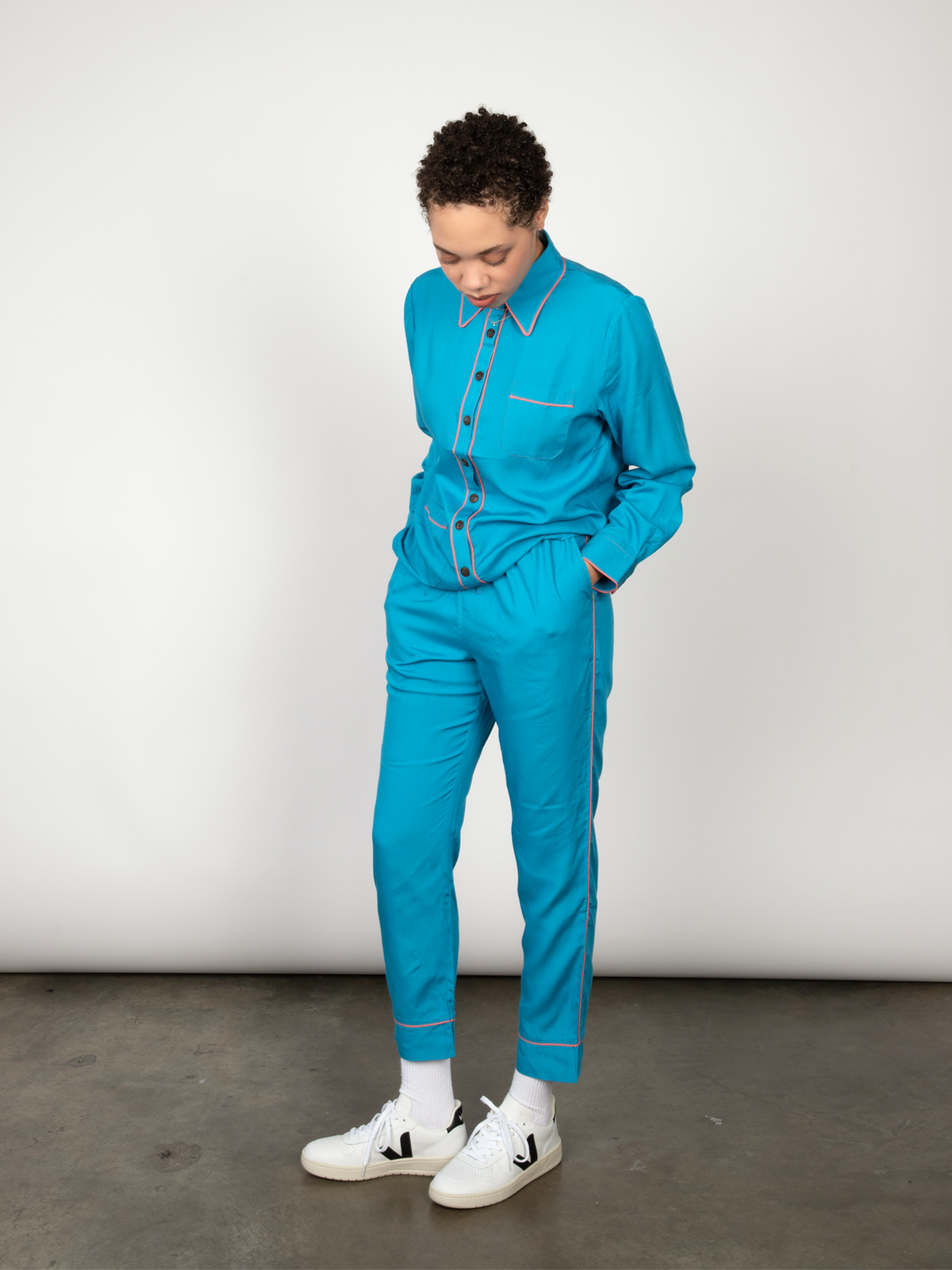 Woman wears a blue pajama set and poses in a studio.