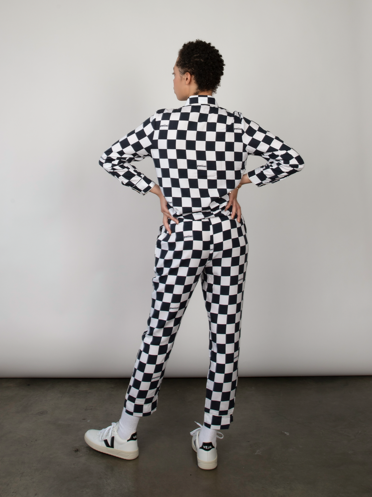 Woman with her back turned wears a black and white checkered pajama set.