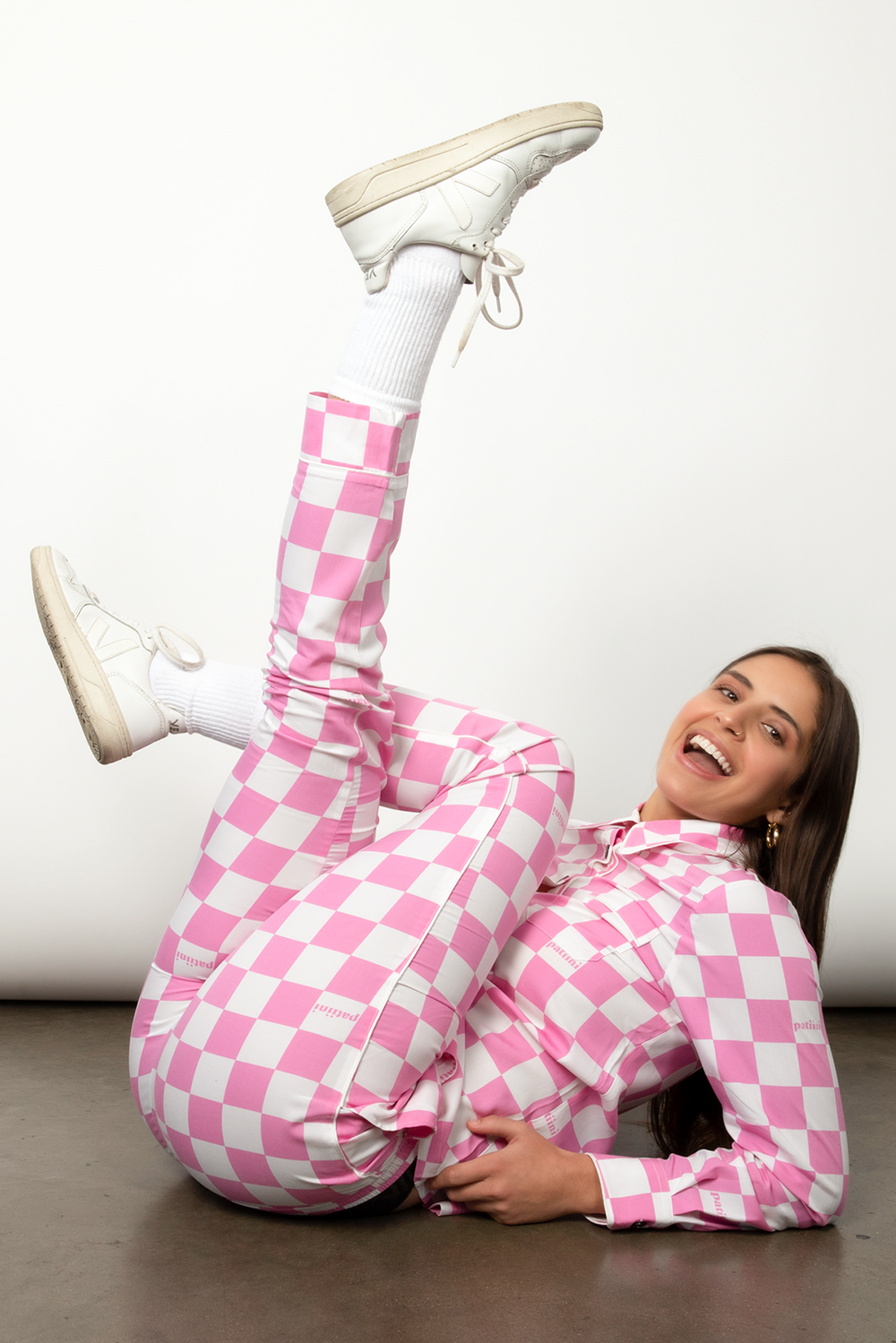 Woman smiles for a pose wearing a pink and white checkered pajama set.